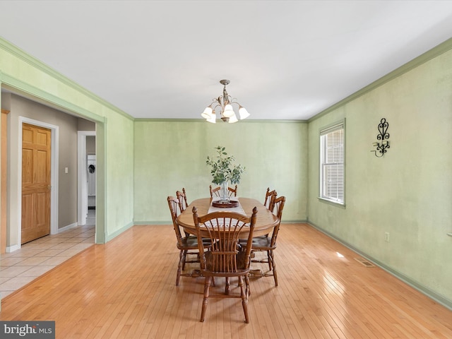 dining room with light hardwood / wood-style flooring, crown molding, and a chandelier