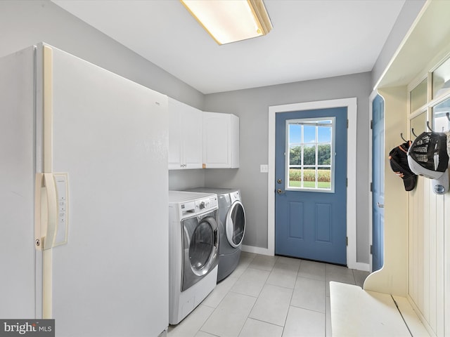 clothes washing area with cabinets, separate washer and dryer, and light tile patterned floors