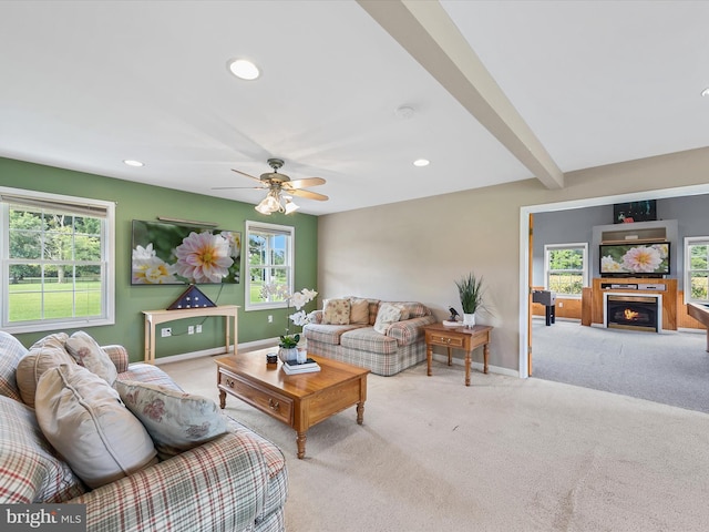 living room featuring ceiling fan, light carpet, beamed ceiling, and a fireplace