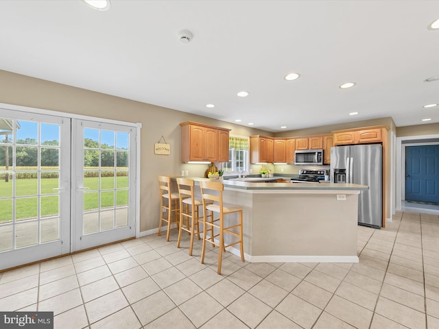 kitchen with a kitchen breakfast bar, light tile patterned floors, appliances with stainless steel finishes, and kitchen peninsula