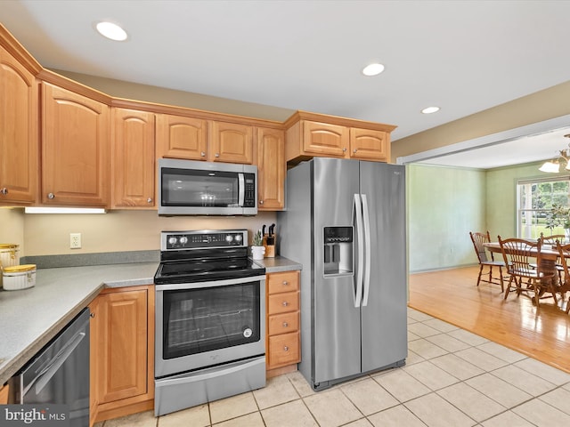 kitchen featuring appliances with stainless steel finishes, a notable chandelier, and light tile patterned flooring