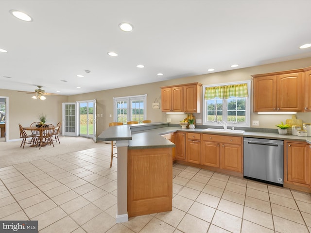 kitchen with kitchen peninsula, ceiling fan, light colored carpet, dishwasher, and sink