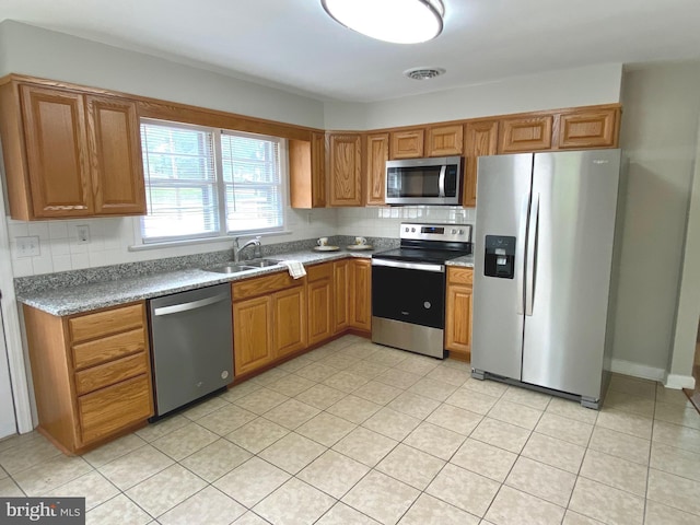 kitchen featuring decorative backsplash, sink, light tile patterned floors, and stainless steel appliances