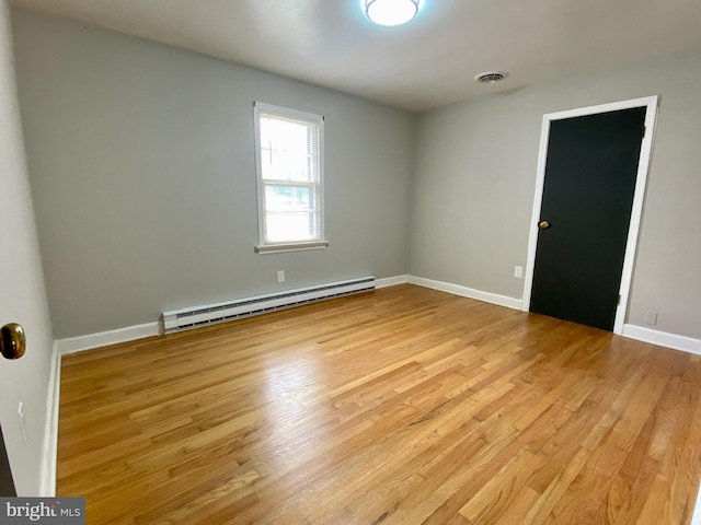 spare room with a baseboard heating unit and light wood-type flooring