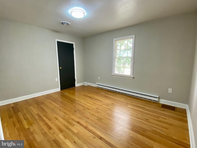 empty room featuring baseboard heating and light hardwood / wood-style flooring