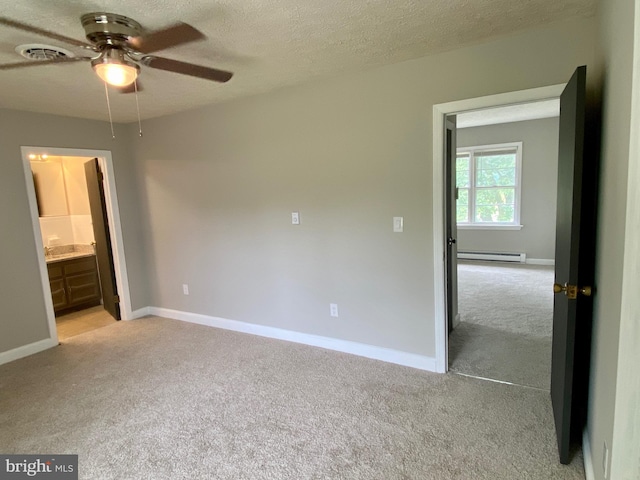 unfurnished bedroom with ceiling fan, a textured ceiling, connected bathroom, light carpet, and baseboard heating