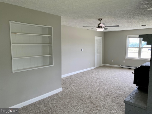 spare room featuring ceiling fan, a baseboard heating unit, a wood stove, and a textured ceiling