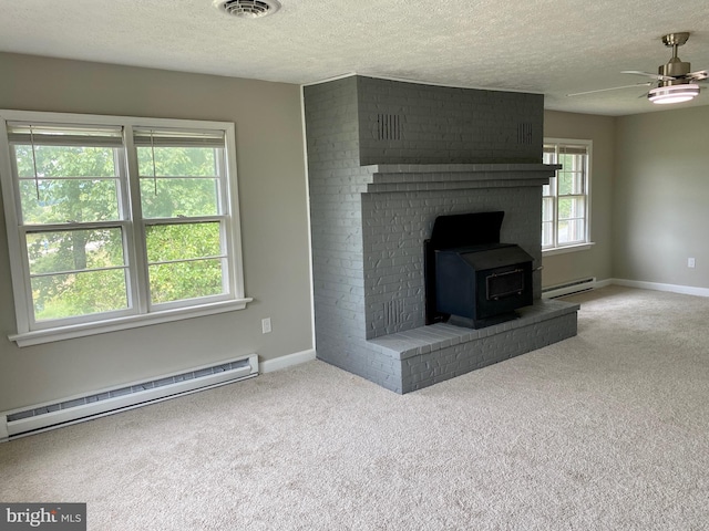 unfurnished living room with a baseboard radiator, a textured ceiling, a wood stove, and carpet flooring