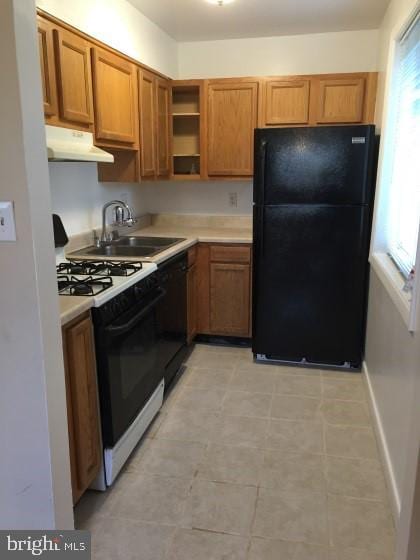 kitchen featuring black appliances, sink, and light tile patterned floors