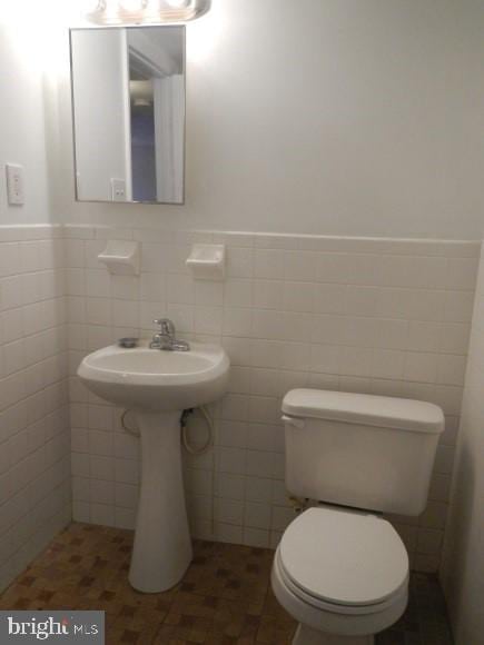 bathroom with tile walls and toilet