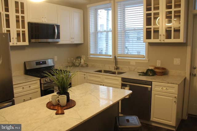 kitchen featuring light stone counters, stainless steel appliances, white cabinetry, and sink