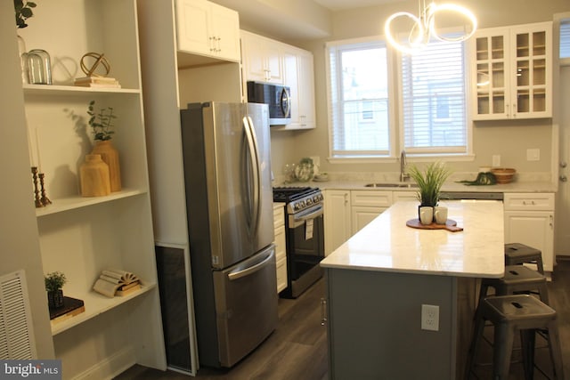 kitchen with a center island, appliances with stainless steel finishes, decorative light fixtures, and white cabinets