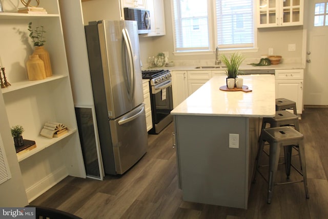 kitchen with white cabinets, stainless steel appliances, dark hardwood / wood-style flooring, a kitchen bar, and a kitchen island