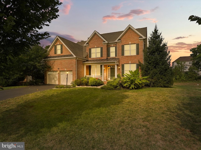 view of front of house featuring a garage, covered porch, and a lawn