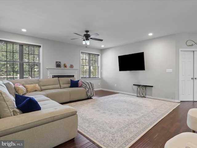 living room featuring dark wood-type flooring and ceiling fan