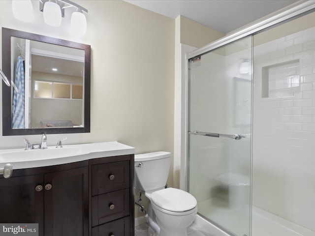 bathroom featuring vanity, a shower with shower door, and toilet