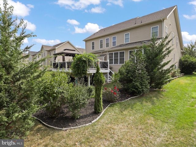 back of property featuring a gazebo, a wooden deck, and a lawn