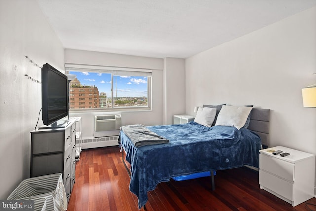 bedroom featuring a baseboard radiator, dark hardwood / wood-style flooring, and an AC wall unit