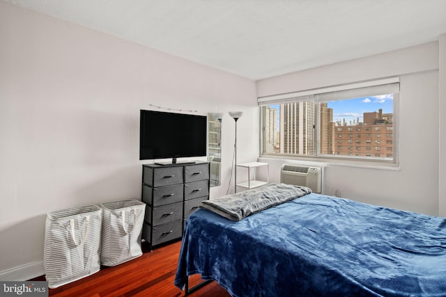 bedroom with dark hardwood / wood-style flooring and a wall unit AC