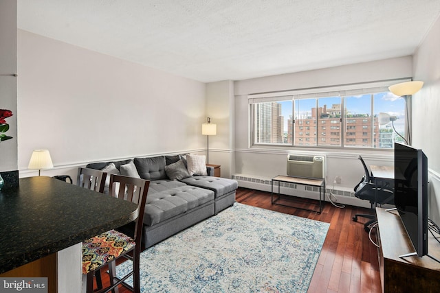 living room featuring a wall mounted AC, a textured ceiling, a baseboard heating unit, and dark hardwood / wood-style floors