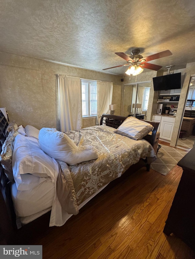 bedroom with ceiling fan, hardwood / wood-style floors, and a textured ceiling