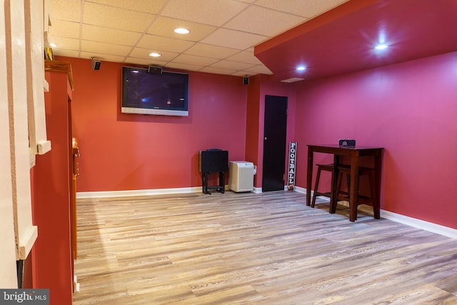 interior space with a paneled ceiling and light hardwood / wood-style flooring