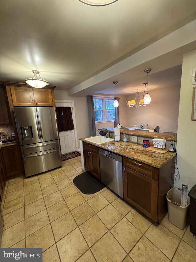 kitchen with pendant lighting, light tile patterned floors, stainless steel appliances, and stone countertops