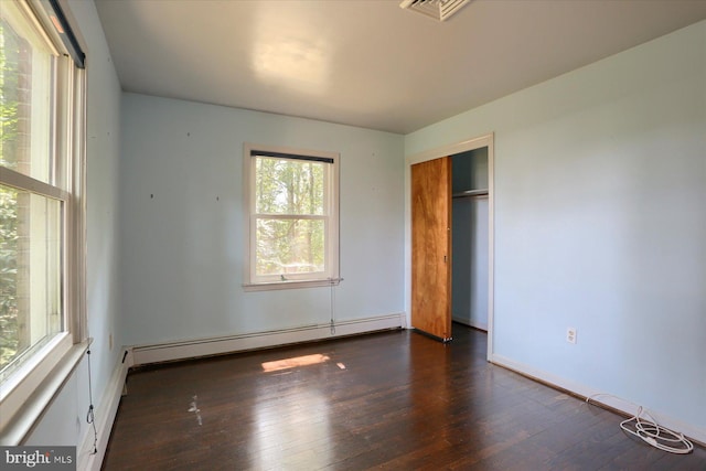 unfurnished bedroom with a closet, a baseboard heating unit, and hardwood / wood-style floors