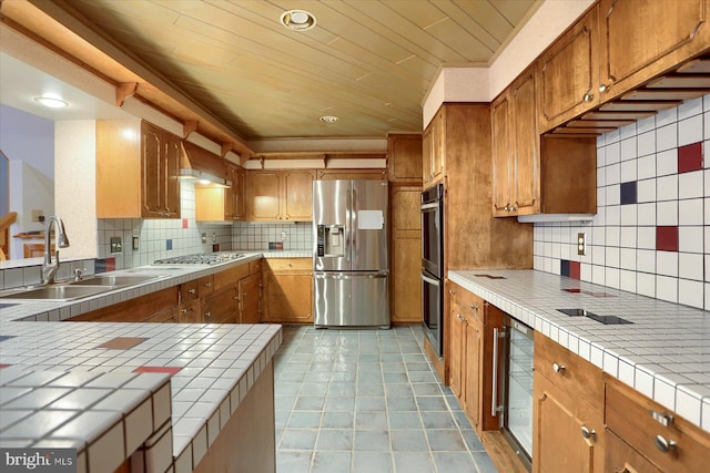 kitchen featuring stainless steel appliances, decorative backsplash, sink, tile counters, and light tile patterned floors