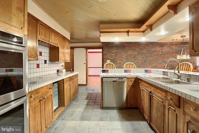 kitchen featuring tasteful backsplash, stainless steel appliances, pendant lighting, sink, and tile countertops