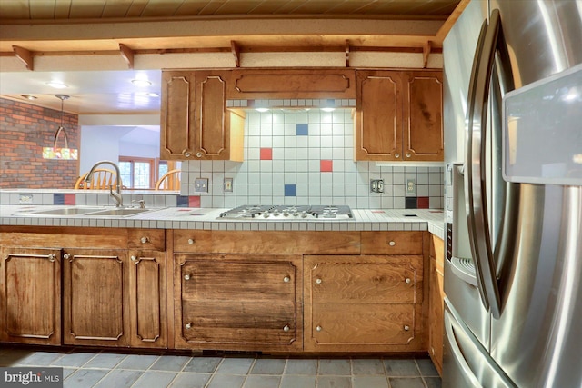 kitchen featuring stainless steel appliances, decorative backsplash, sink, beam ceiling, and tile counters