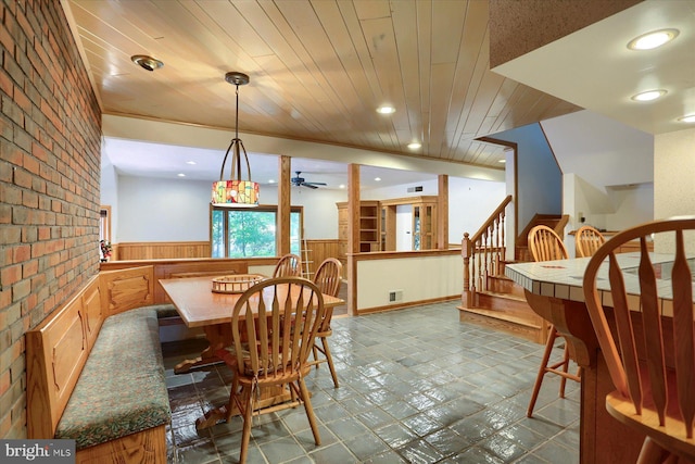 tiled dining area featuring wood ceiling, brick wall, and ceiling fan