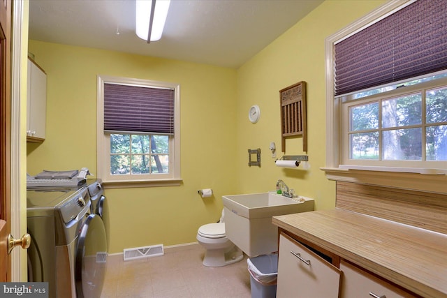 bathroom featuring separate washer and dryer, toilet, a healthy amount of sunlight, and tile patterned flooring