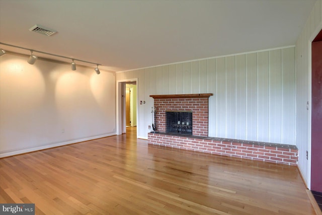 unfurnished living room featuring hardwood / wood-style flooring, a fireplace, and track lighting