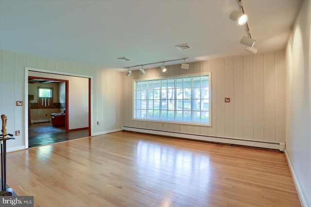 unfurnished living room with light hardwood / wood-style floors, rail lighting, and a baseboard radiator