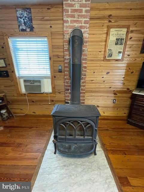 details with cooling unit, wooden walls, wood-type flooring, and a wood stove