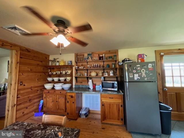 kitchen with wooden walls, stainless steel appliances, and ceiling fan