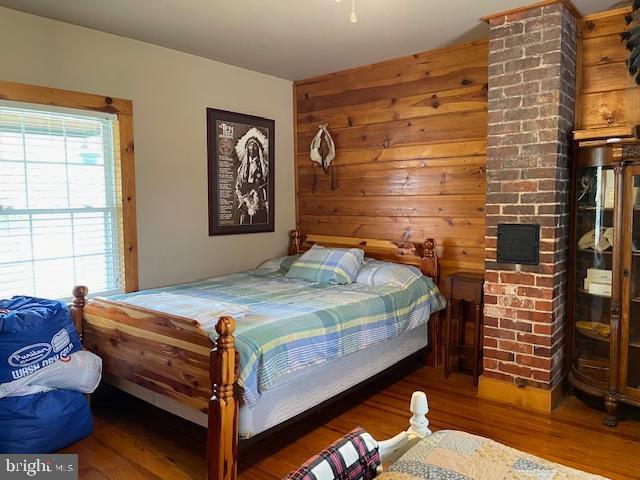 bedroom featuring dark hardwood / wood-style flooring, multiple windows, and wood walls