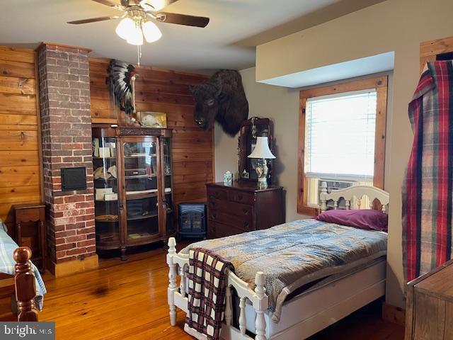 bedroom featuring ceiling fan, wooden walls, and light hardwood / wood-style floors