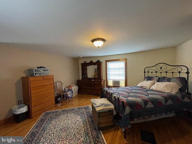 bedroom with cooling unit and light hardwood / wood-style flooring