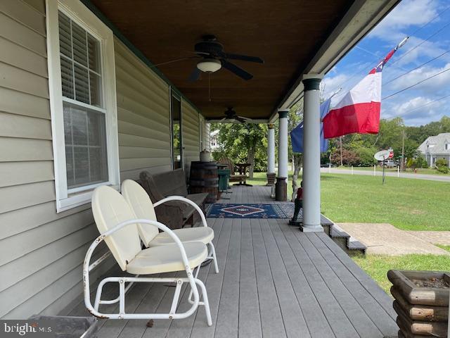 deck featuring a lawn, ceiling fan, and covered porch