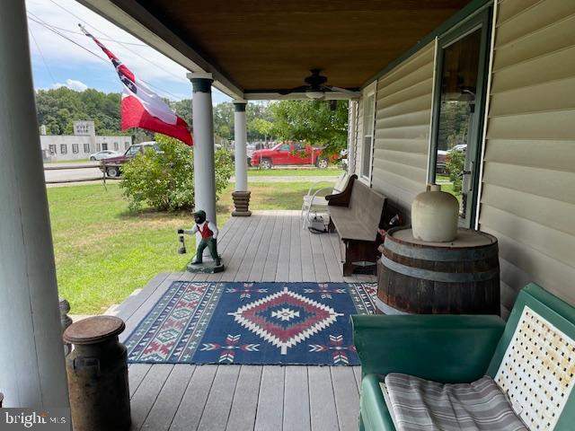 deck with a yard, ceiling fan, and a porch