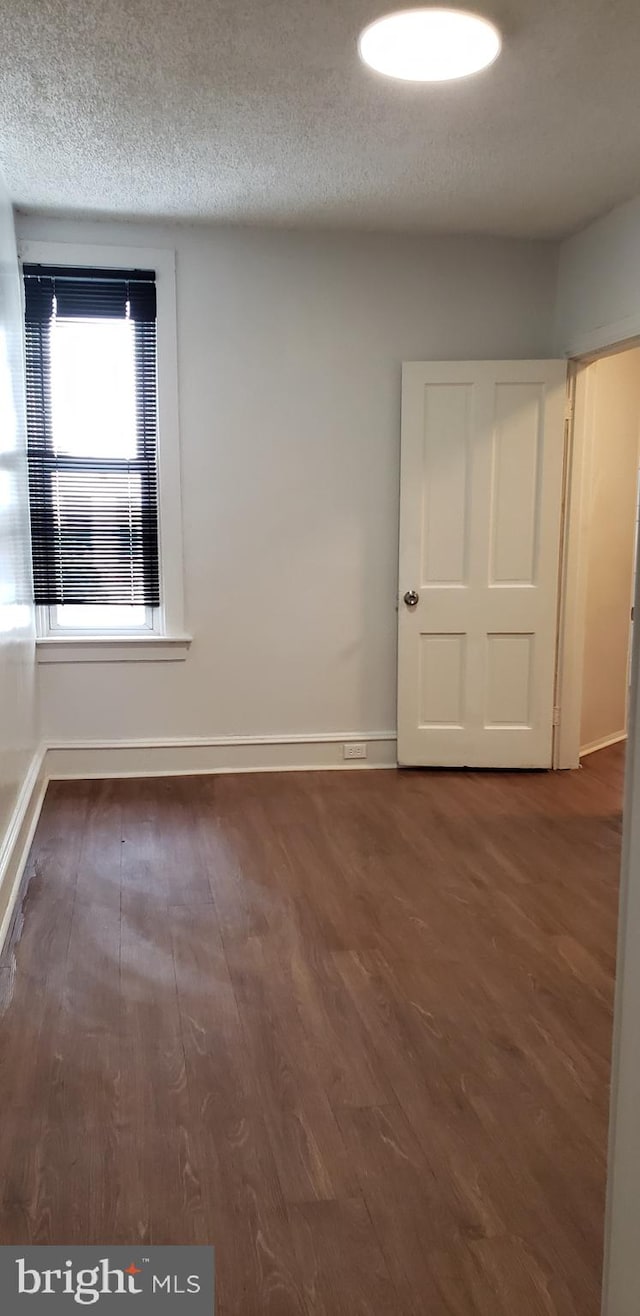 empty room with a textured ceiling and dark hardwood / wood-style flooring