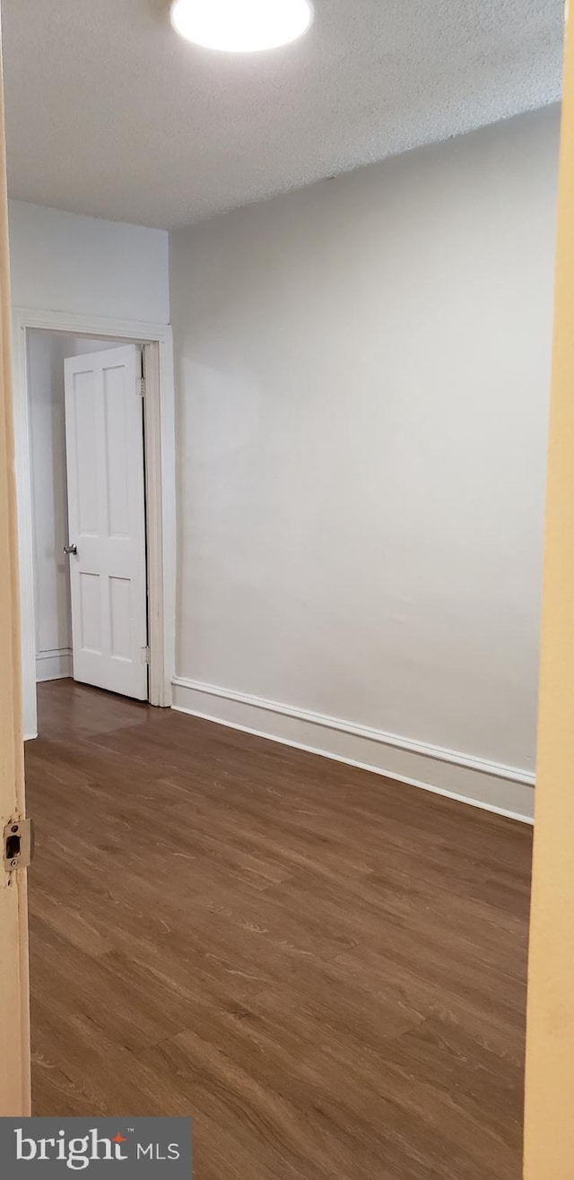 unfurnished room featuring a textured ceiling and dark hardwood / wood-style floors