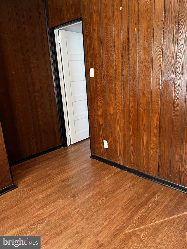 empty room with wood walls and hardwood / wood-style floors