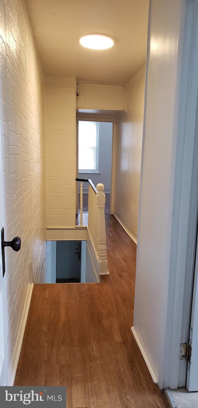 hall with dark wood-type flooring and brick wall