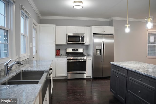 kitchen featuring stainless steel appliances, pendant lighting, white cabinets, and sink