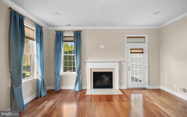 unfurnished living room featuring crown molding, wood-type flooring, and a tile fireplace