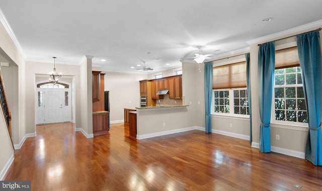 unfurnished living room featuring crown molding, dark wood-type flooring, and ceiling fan with notable chandelier