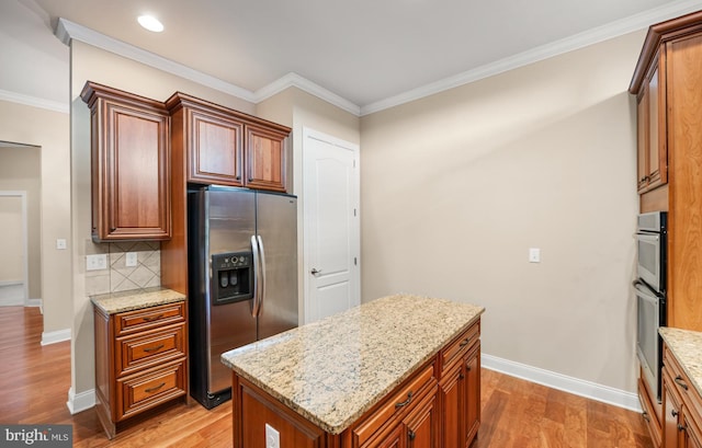 kitchen featuring light stone counters, decorative backsplash, stainless steel appliances, and a kitchen island